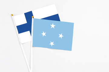 Micronesia and Finland stick flags on white background. High quality fabric, miniature national flag. Peaceful global concept.White floor for copy space.