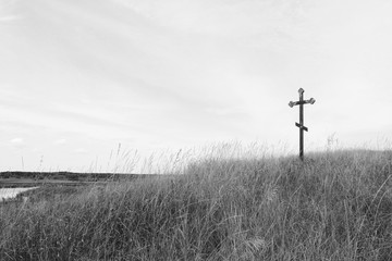 Black-and-white photo with wooden cross on sky background