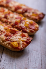 Pizza baguettes with salami and white wooden background