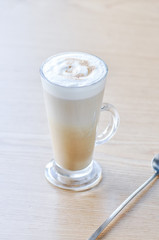 One tall glass of latte on a table.