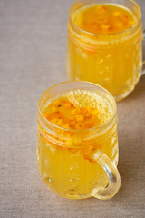 Sea buckthorn tea in glass mugs on brown textile background 