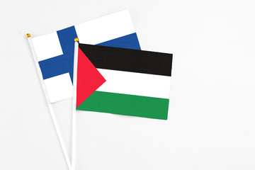 Palestine and Finland stick flags on white background. High quality fabric, miniature national flag. Peaceful global concept.White floor for copy space.