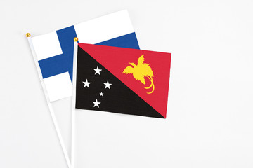 Papua New Guinea and Finland stick flags on white background. High quality fabric, miniature national flag. Peaceful global concept.White floor for copy space.