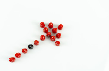 Many red meeple shaped like an arrow and one black meeple between, white background and copy space