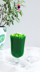 green drink with marshmallows and a flower in the background