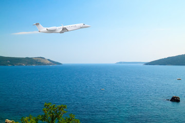 Private jet business plane flies low over sea of  background of beautiful calm seascape with white clouds