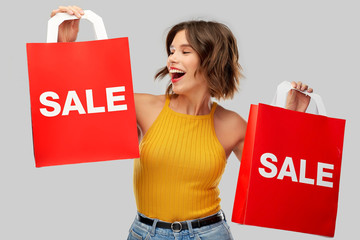 sale and people concept - happy smiling young woman in mustard yellow top and jeans with shopping...