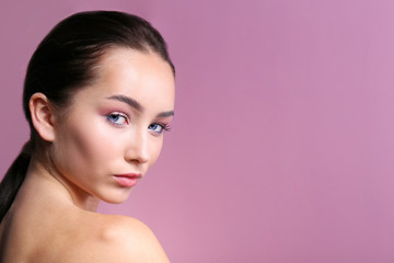 Fototapeta premium Portrait of young beautiful woman with perfectly clean face skin wearing professional make up. Female with long black hair. Close up, copy space background.