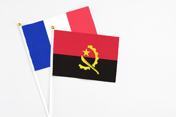 Angola and France stick flags on white background. High quality fabric, miniature national flag. Peaceful global concept.White floor for copy space.