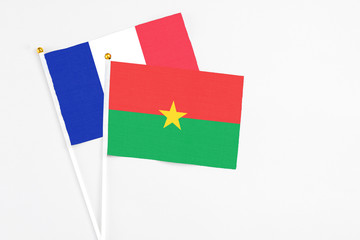 Burkina Faso and France stick flags on white background. High quality fabric, miniature national flag. Peaceful global concept.White floor for copy space.