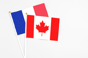 Canada and France stick flags on white background. High quality fabric, miniature national flag. Peaceful global concept.White floor for copy space.