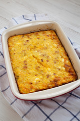 Home-baked Cheesy Amish Breakfast Casserole on a white wooden surface, low angle view. Closeup.