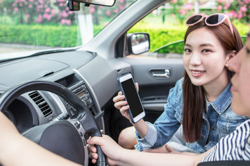 Fototapeta na wymiar LWTWL0025948 Business woman sitting in car and using her smartphone. Mockup image with female driver and phone screen