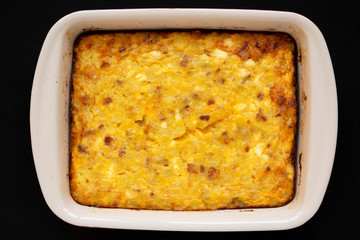 Homemade Cheesy Amish Breakfast Casserole on a black background, overhead view. Flat lay, from above, top view. Close-up.
