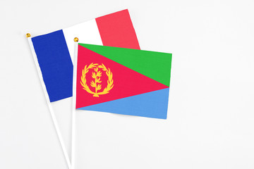 Eritrea and France stick flags on white background. High quality fabric, miniature national flag. Peaceful global concept.White floor for copy space.