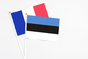 Estonia and France stick flags on white background. High quality fabric, miniature national flag. Peaceful global concept.White floor for copy space.