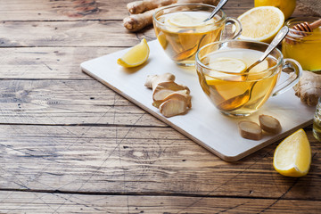 Two cups of natural herbal tea ginger lemon and honey on a wooden background. Copy space