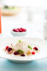 Rice porridge with milk and cranberry in a plate on a table.