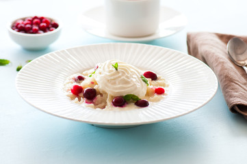 Rice porridge with milk and cranberry in a plate on a table.