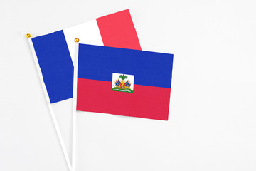 Haiti and France stick flags on white background. High quality fabric, miniature national flag. Peaceful global concept.White floor for copy space.