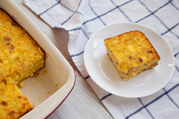 Homemade Cheesy Amish Breakfast Casserole on a white wooden surface, low angle view. Close-up.