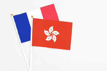 Hong Kong and France stick flags on white background. High quality fabric, miniature national flag. Peaceful global concept.White floor for copy space.