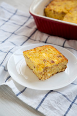 Homemade Cheesy Amish Breakfast Casserole on a white wooden background, side view. Close-up.