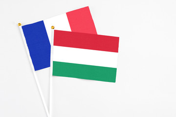 Hungary and France stick flags on white background. High quality fabric, miniature national flag. Peaceful global concept.White floor for copy space.