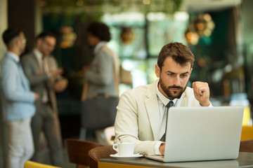 Handsome young businessman working at laptop