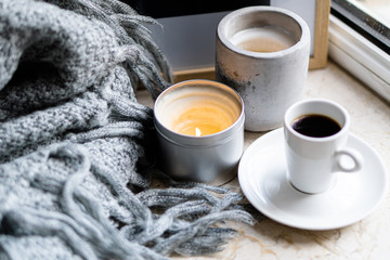 Burning candles, gray blanket and cup of coffee