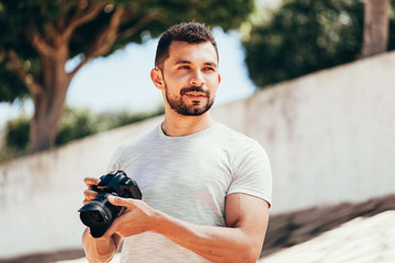 Young man with DSLR camera in city