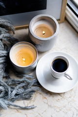 Burning candles, gray blanket and cup of coffee