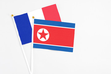 North Korea and France stick flags on white background. High quality fabric, miniature national flag. Peaceful global concept.White floor for copy space.