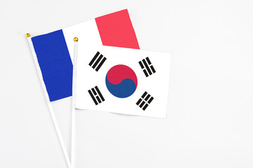 South Korea and France stick flags on white background. High quality fabric, miniature national flag. Peaceful global concept.White floor for copy space.