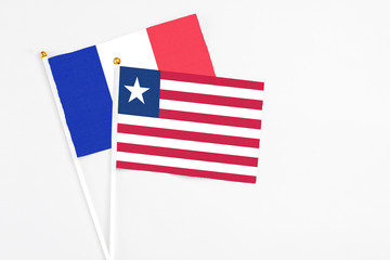 Liberia and France stick flags on white background. High quality fabric, miniature national flag. Peaceful global concept.White floor for copy space.