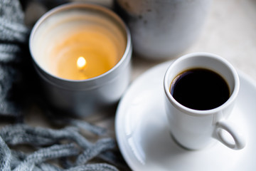Burning candles, gray blanket and cup of coffee