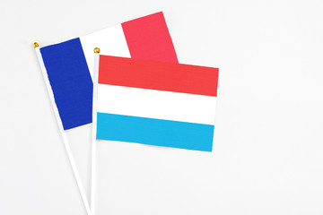 Luxembourg and France stick flags on white background. High quality fabric, miniature national flag. Peaceful global concept.White floor for copy space.