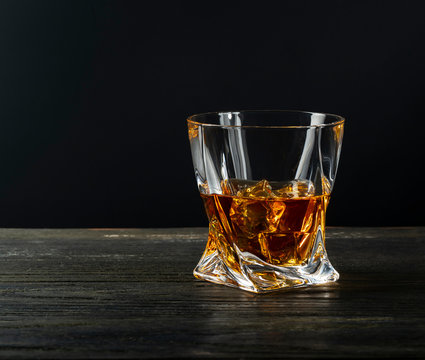 Glass of whiskey, classy, with ice, on wooden table