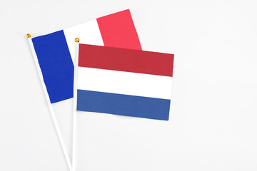 Netherlands and France stick flags on white background. High quality fabric, miniature national flag. Peaceful global concept.White floor for copy space.