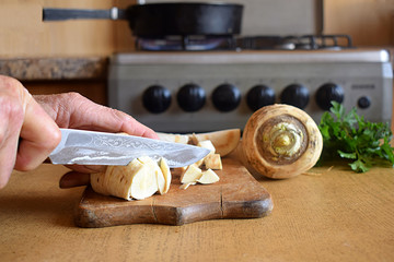Slicing parsnip on a cutting board.