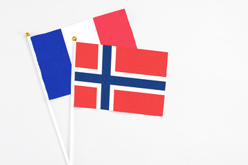 Obraz premium Norway and France stick flags on white background. High quality fabric, miniature national flag. Peaceful global concept.White floor for copy space.