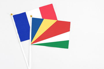 Seychelles and France stick flags on white background. High quality fabric, miniature national flag. Peaceful global concept.White floor for copy space.