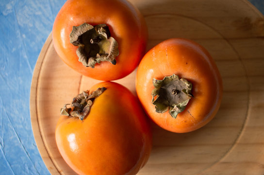 Plate of fresh and ripe persimmons. Top view and copy space.