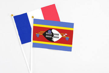 Swaziland and France stick flags on white background. High quality fabric, miniature national flag. Peaceful global concept.White floor for copy space.