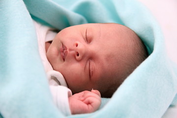 baby sleeping wrapped up in blanket just been cared for after having a good sleep in bed stock...