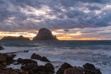 Small wooden pier in Cala d'Hort bay and view of Es Vedra island, Ibiza island, Spain