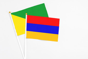 Armenia and French Guiana stick flags on white background. High quality fabric, miniature national flag. Peaceful global concept.White floor for copy space.