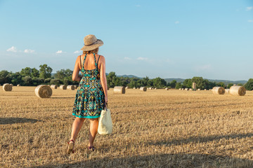 woman walking on wheat stubble towards the straw bales