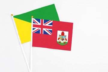 Bermuda and French Guiana stick flags on white background. High quality fabric, miniature national flag. Peaceful global concept.White floor for copy space.