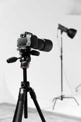 Photo camera with lens on the tripod. Studio shot on gray background